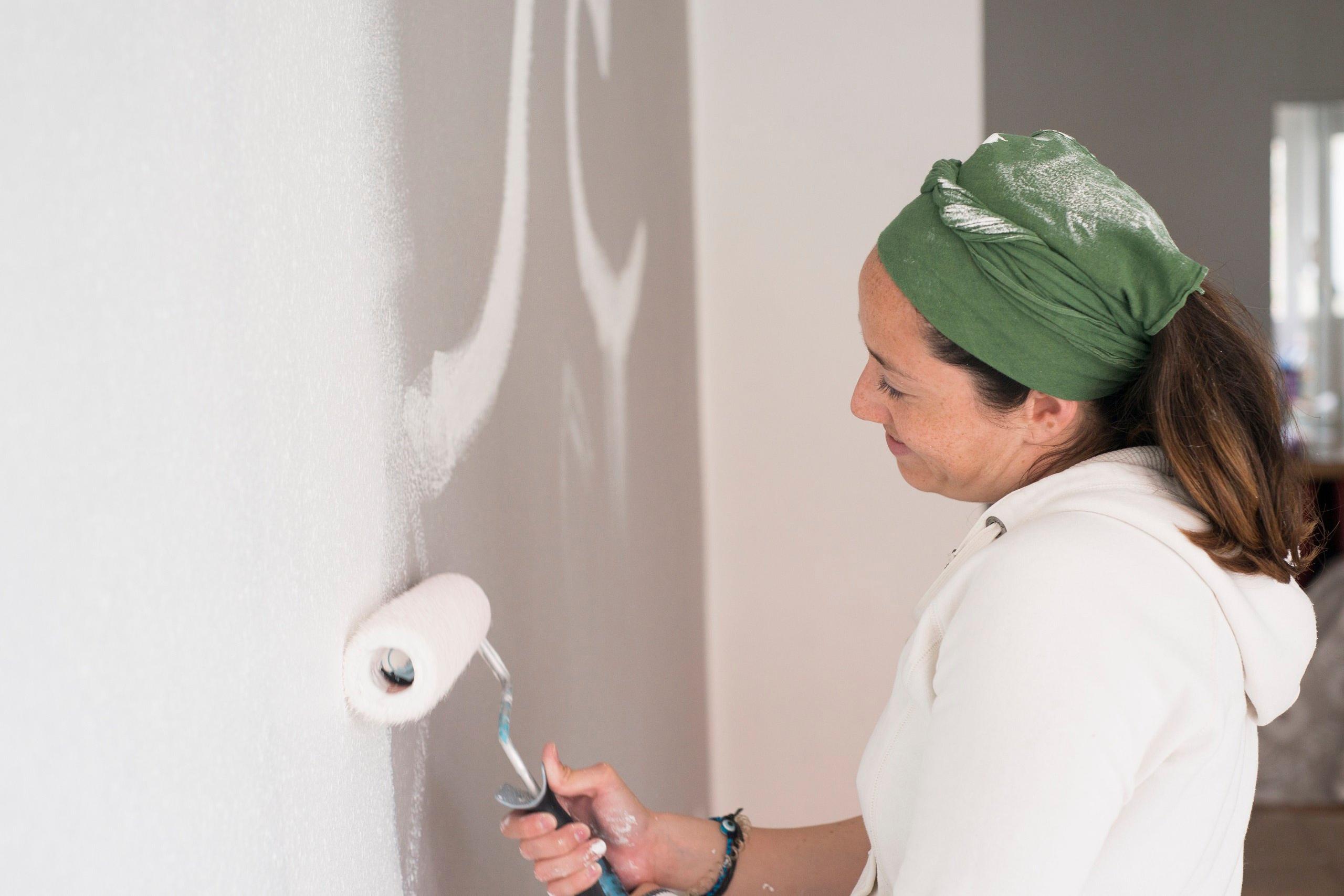 Kvinna målar en innervägg vit.