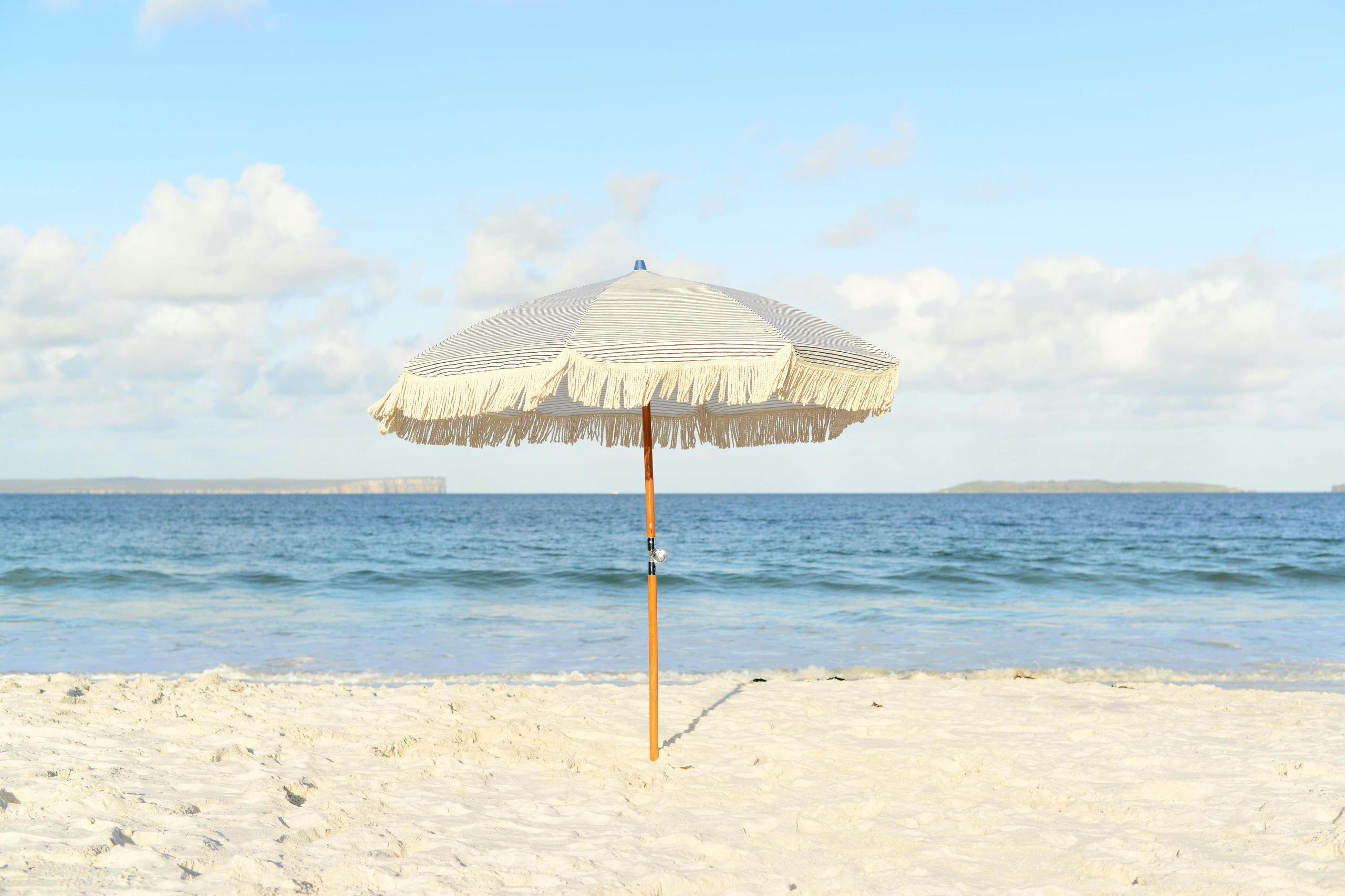 Sandstrand med parasoll vid havet.