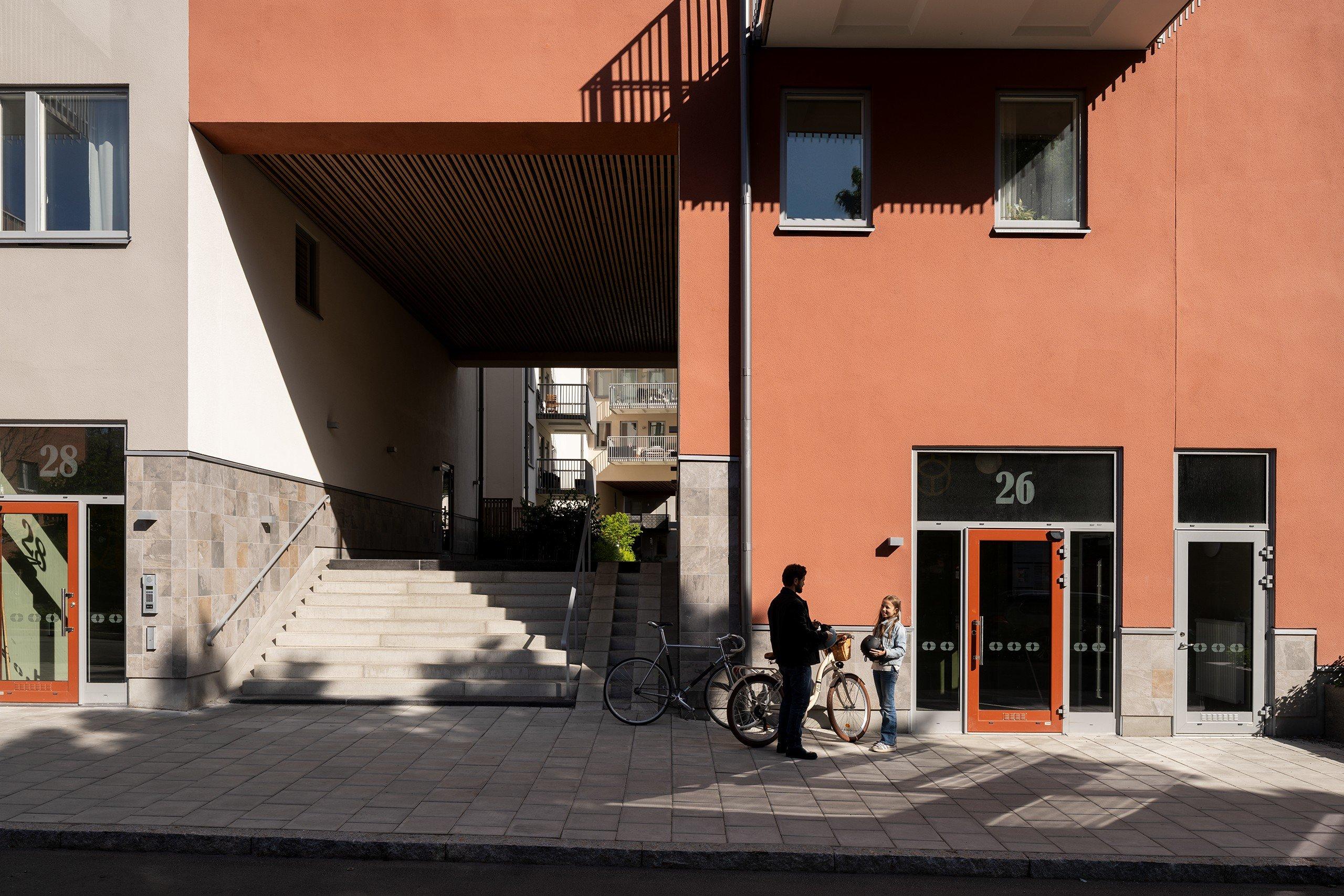 Far och dotter står med cyklar framför porten.