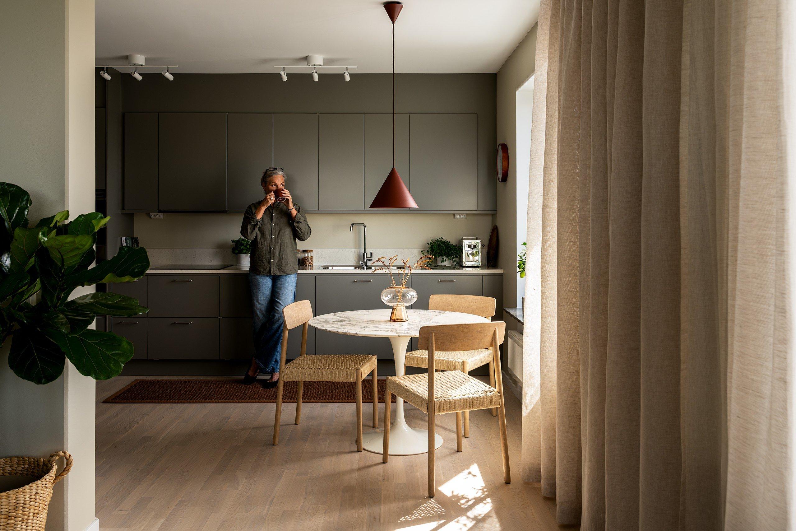 Kvinna dricker en kopp kaffe i ett kök.