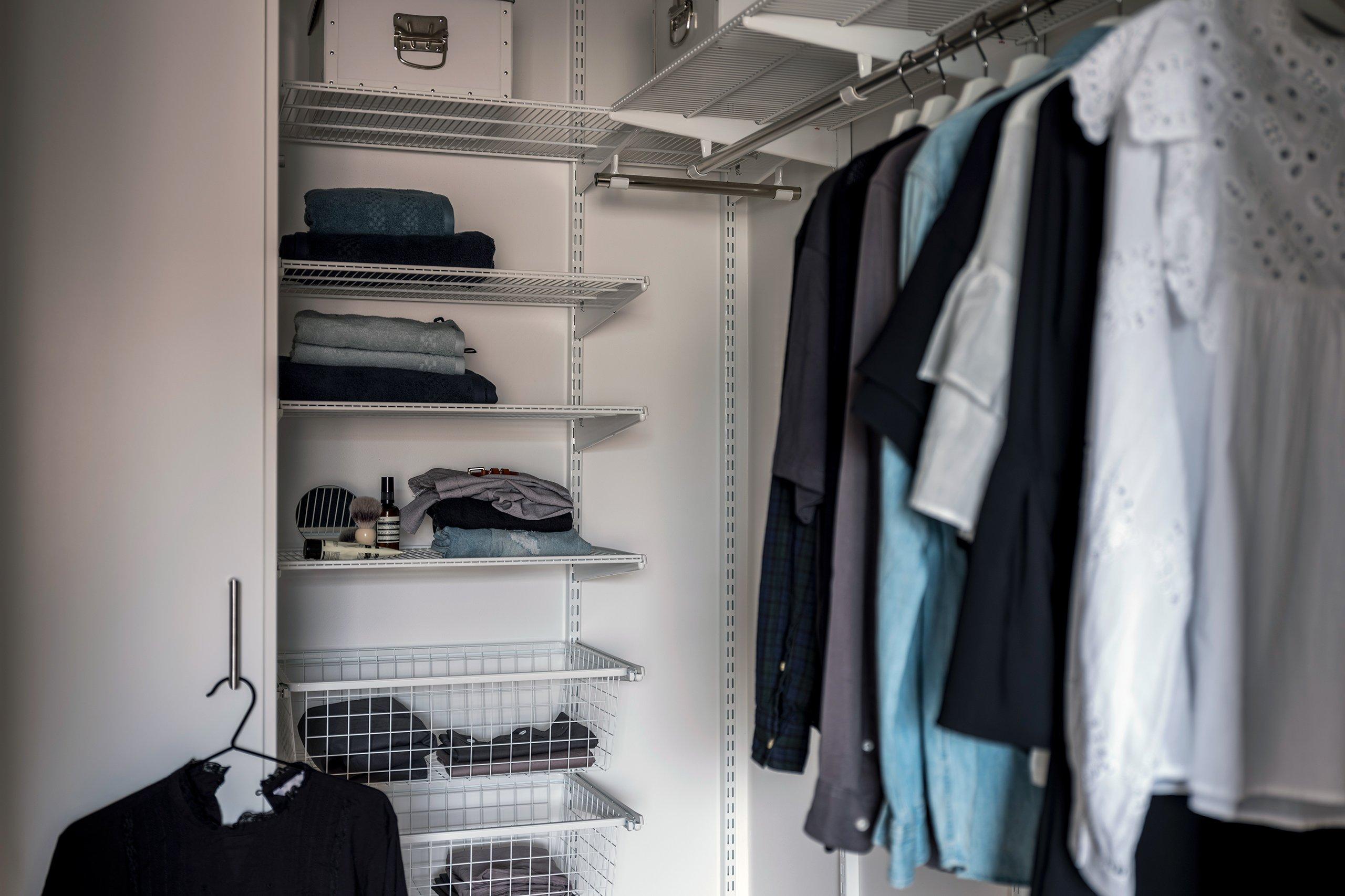 Klädkammare med många kläder, hyllor och trådbackar.
