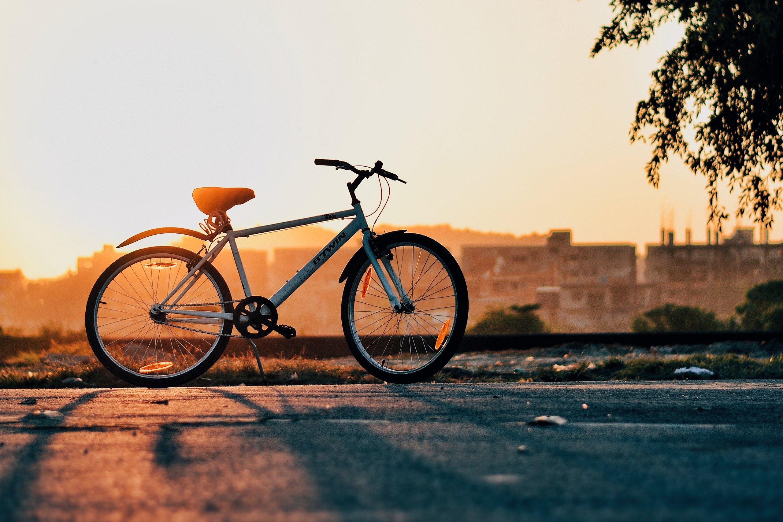 Solnedgång med en parkerad cykel i silhuett.