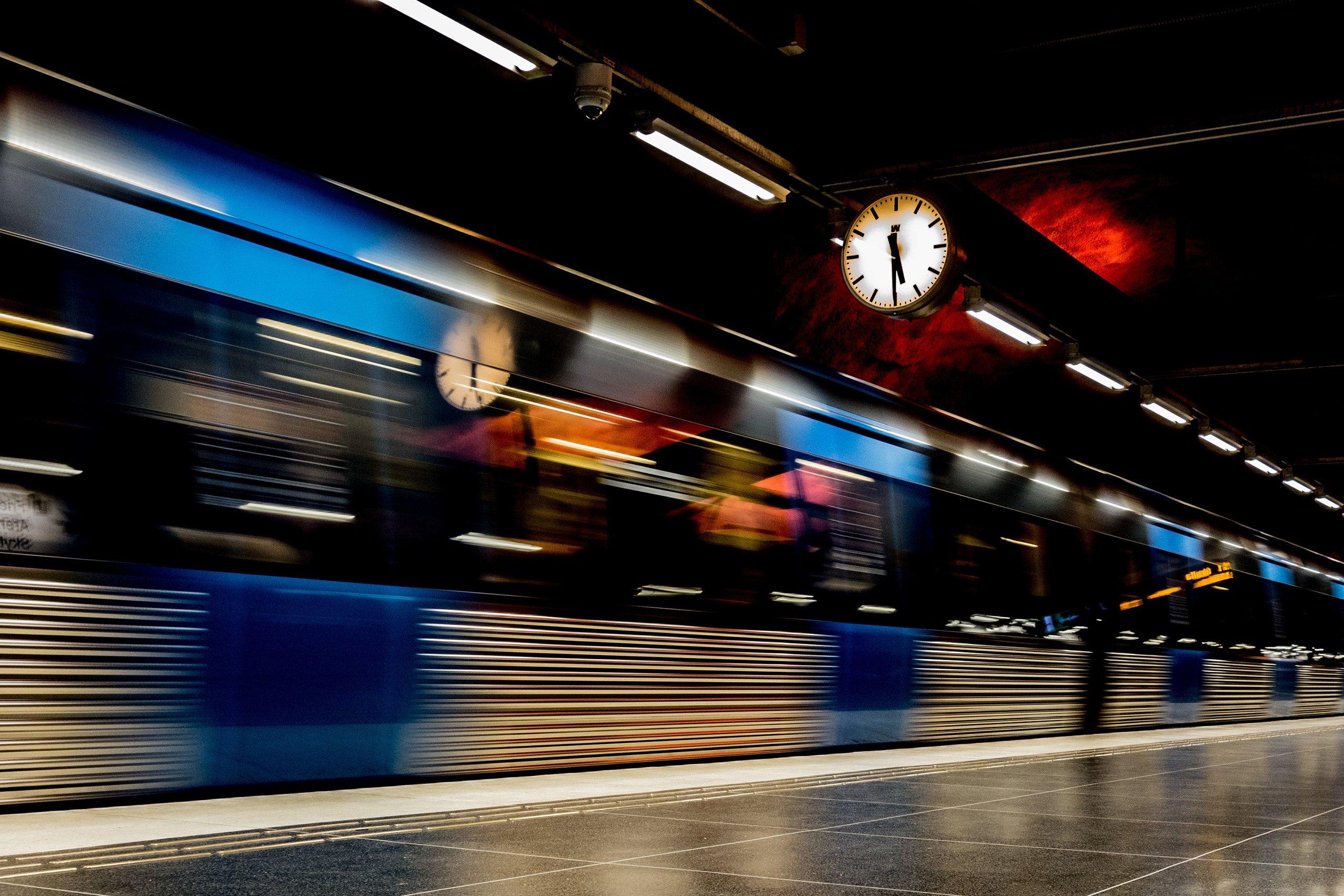 Tunnelbanetåg åker snabbt längs en perrong.