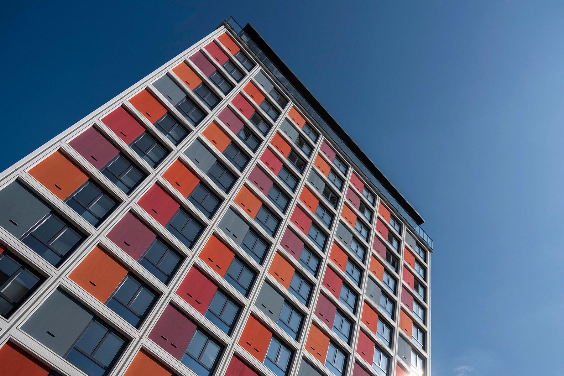 Modern husfasad med starka kulörer mot blå himmel.