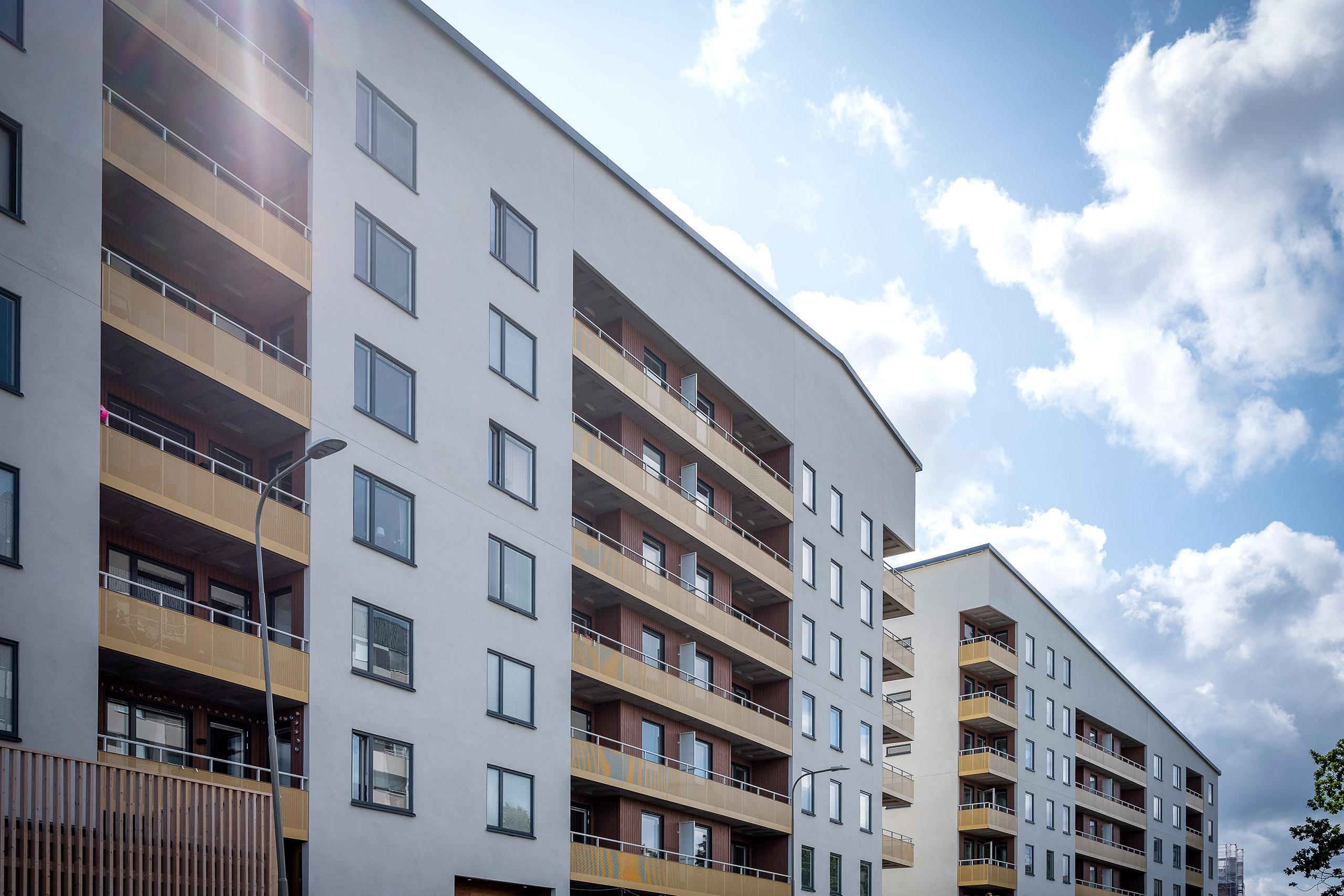 Fasad som visar vitt hus med gula indragna balkonger.