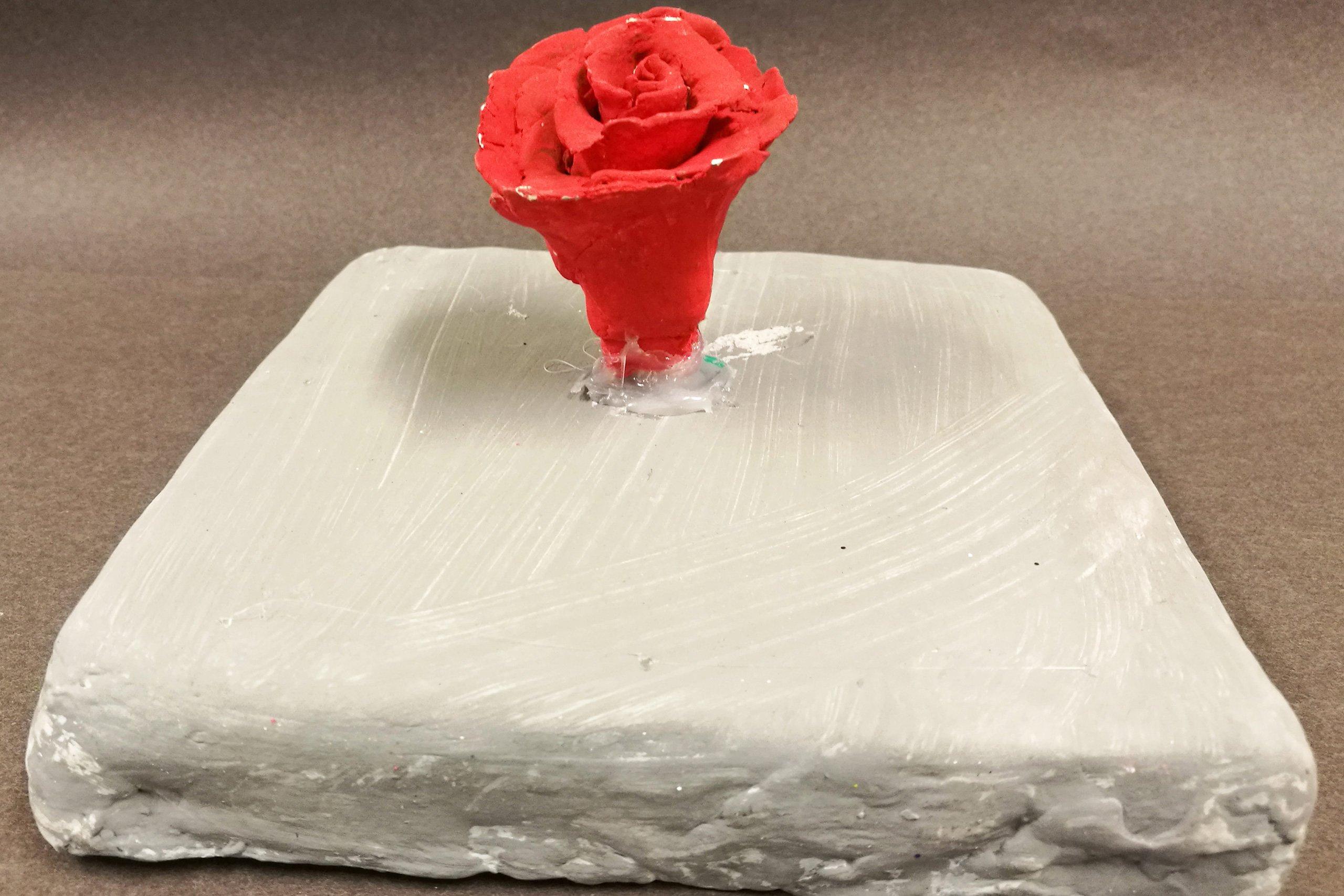 Lermodell av ros på platta.