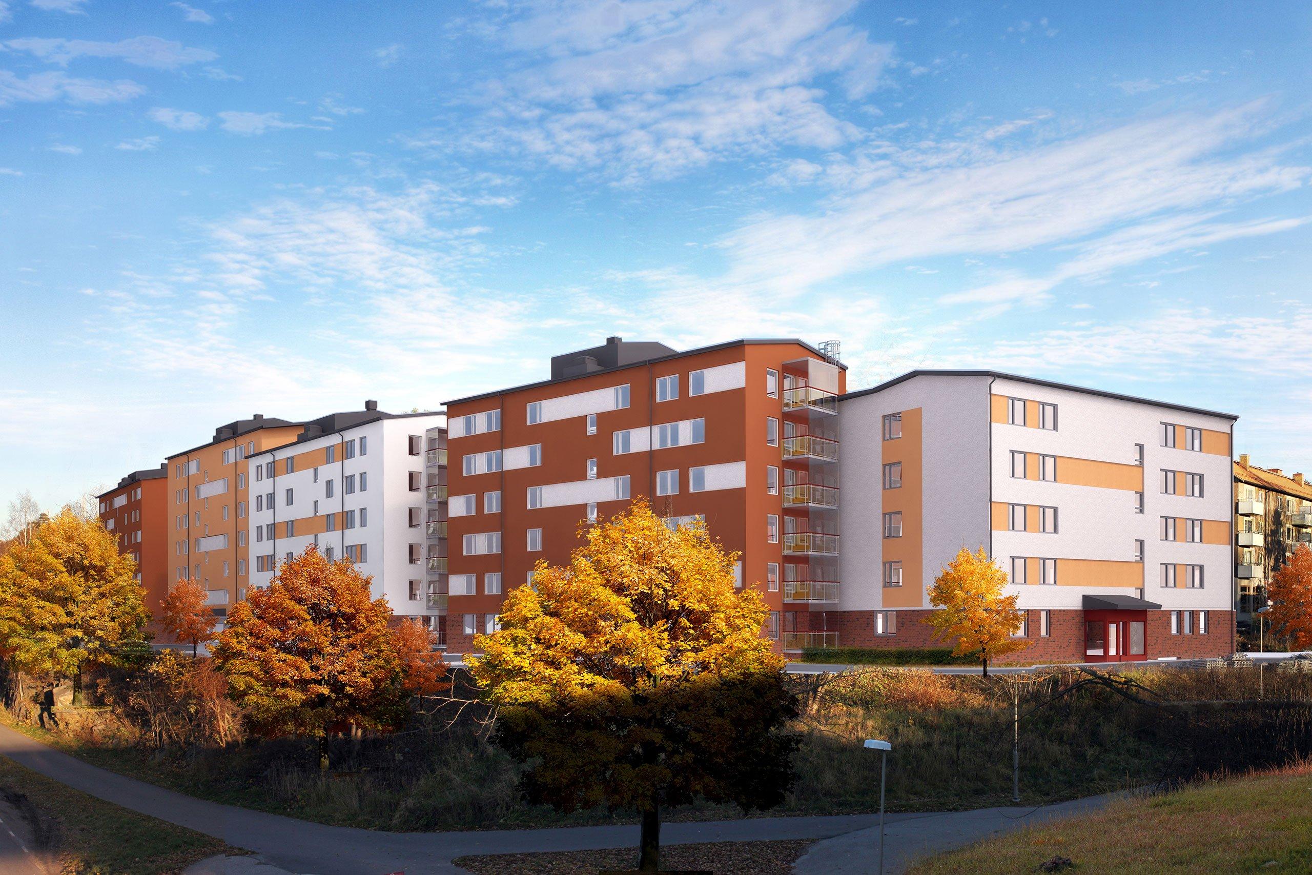 Bostadskvarter i vitt och orange som ligger på en höjd, nedanför står lummiga träd i höstfärger.