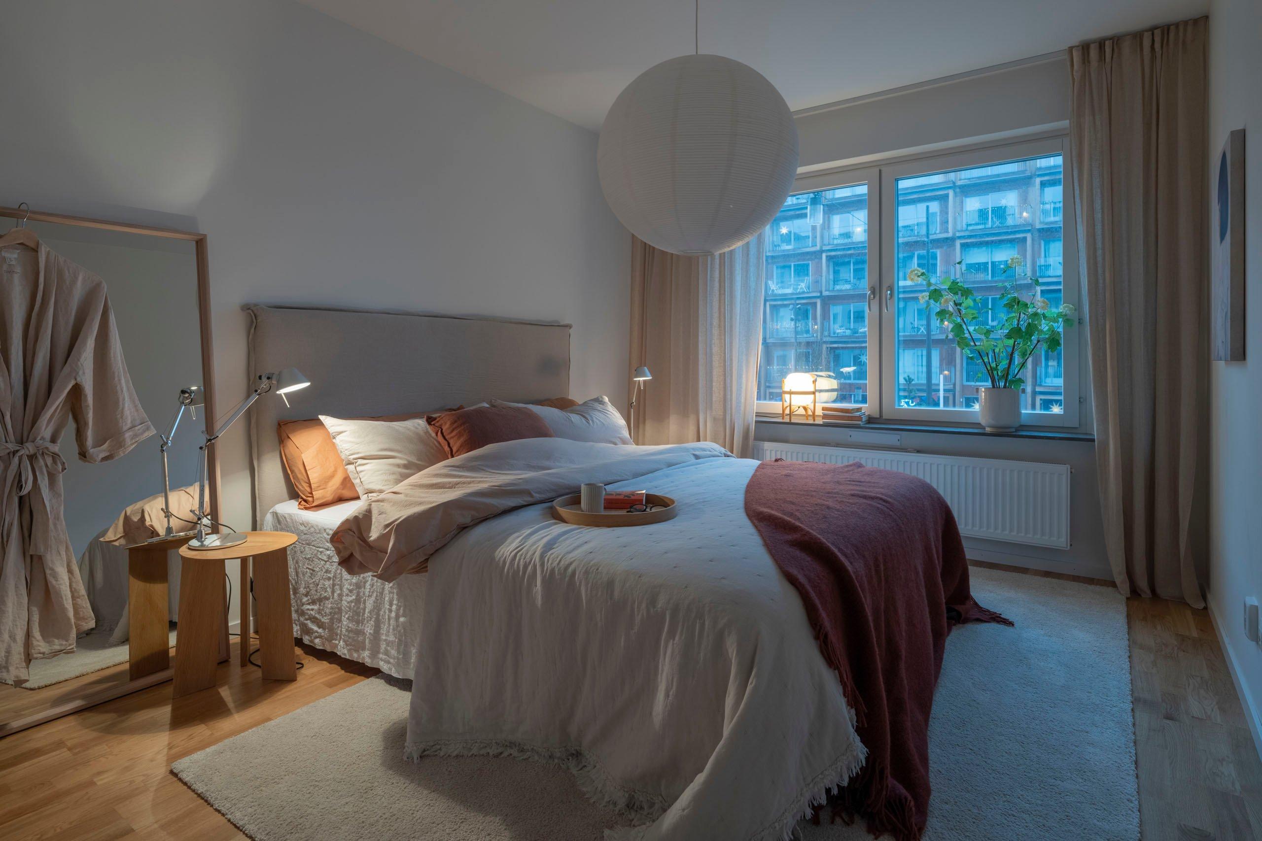 Sovrum med mjuka textilier i kvällsljus.