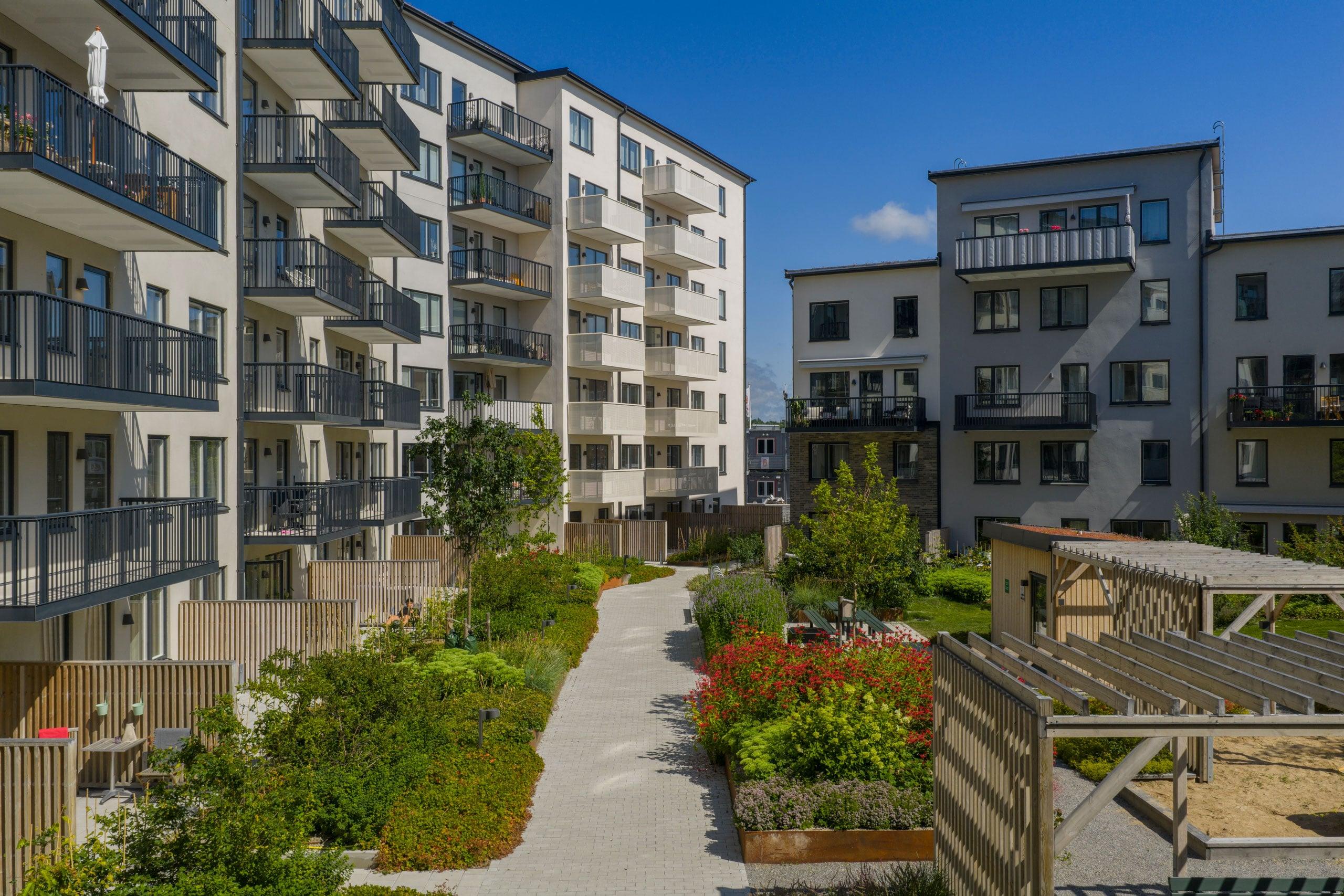 Ljust bostadskvarter med stora balkonger mot grön innergård.