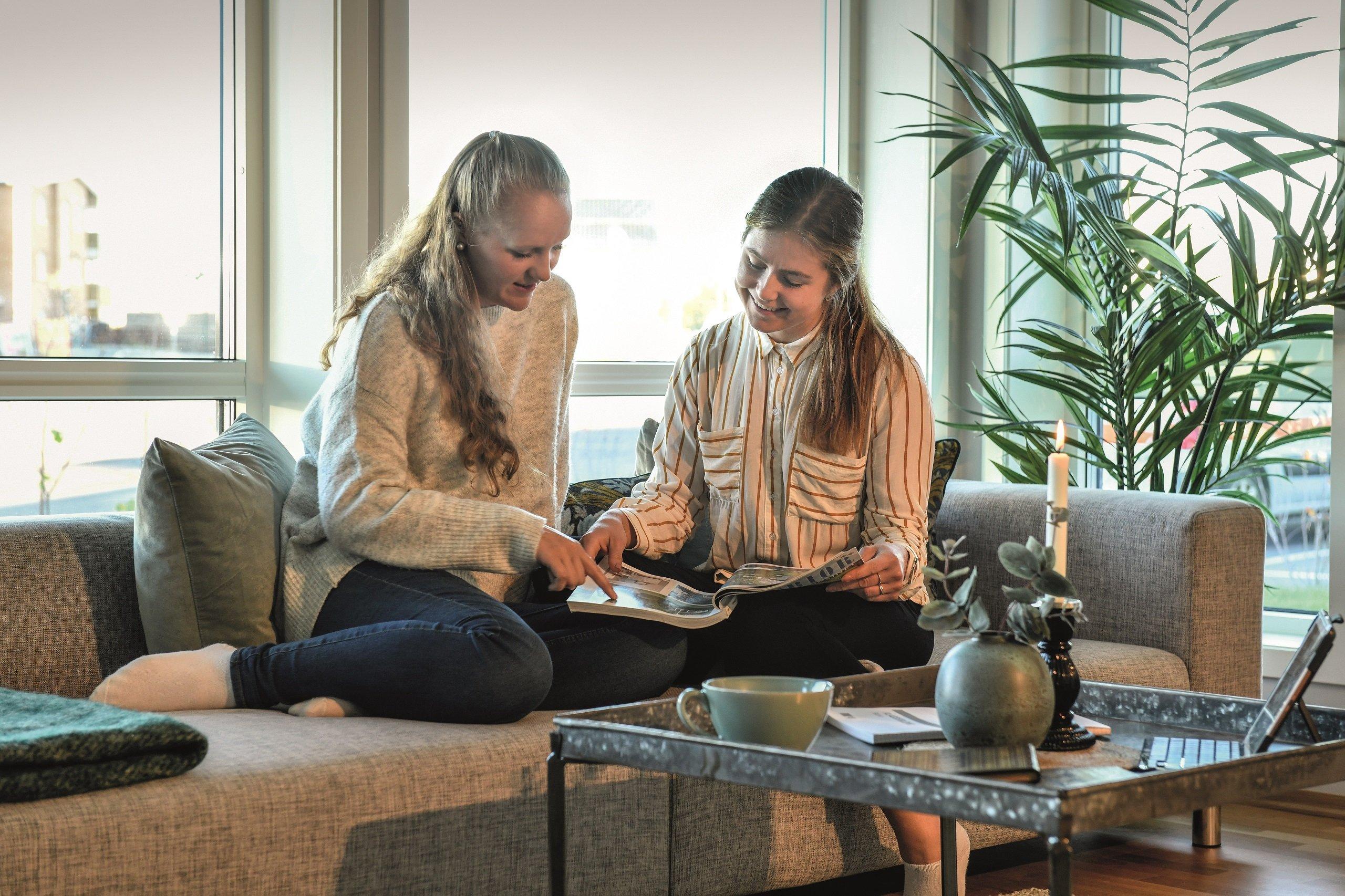 Tjejer i vardagsrum tittar på en magasin