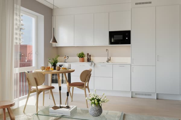 Köksdesignen är stilren med släta luckor och bänkskiva samt bakkantslist i kompositsten (visionsbild).