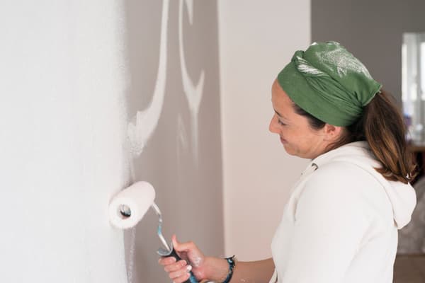 Kvinna målar en innervägg vit.