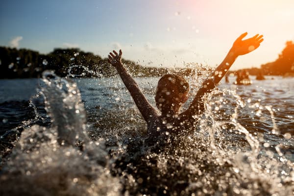 Glatt barn badar i en sjö.