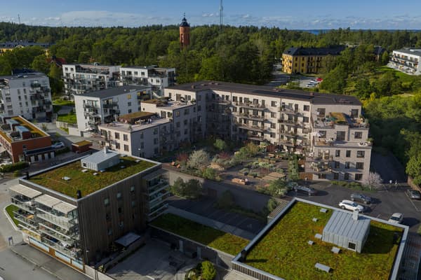 U-format bostadskvarter runt gård med många planteringar.