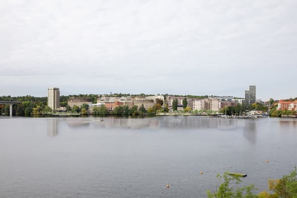 Spegelblankt vatten framför bostadsområde.