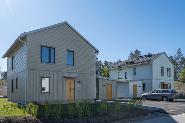 Villa 35 och villa 33 i Skölstadalen med intilliggande förråd, vid hus 33 står en bil parkerad utanför.