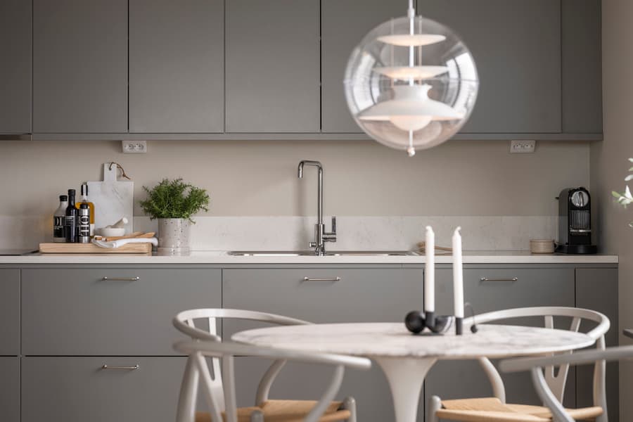 Kök med mörkgrå köksluckor och ett runt matbord med stolar.