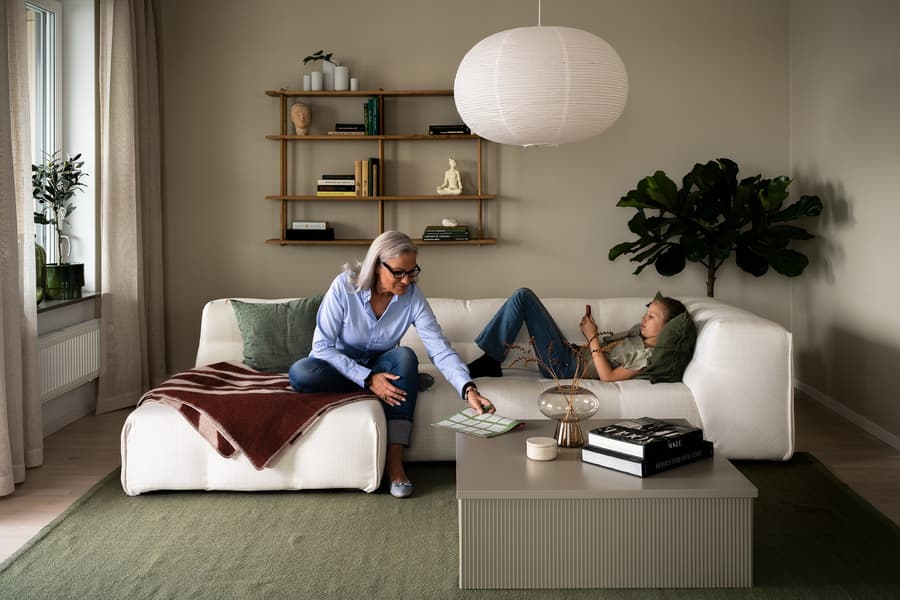 Äldre kvinna med barnbarn i ljus soffa.