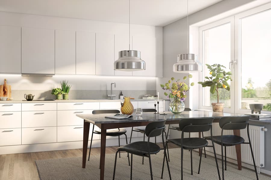 Kök med vita skåpluckor, svart bord och svarta stolar. 