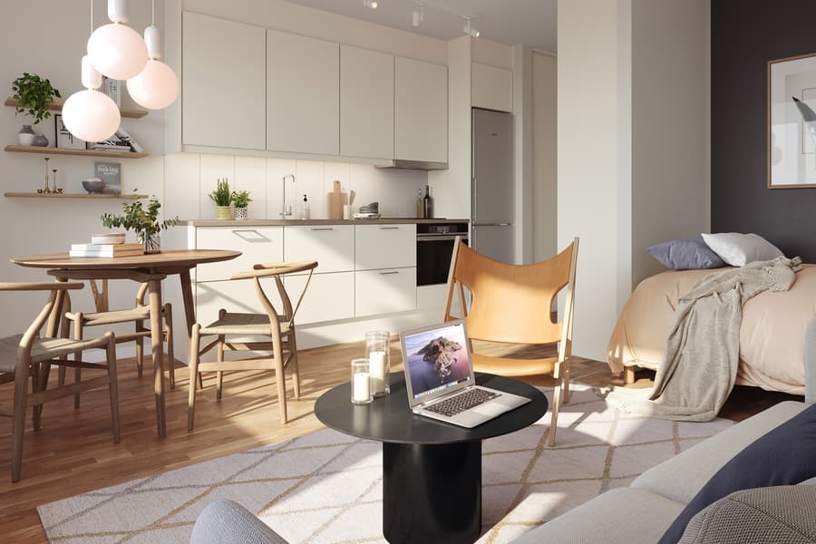 Ljust vardagsrum som vetter mot kök i vitt. Solen skiner in genom fönstret.