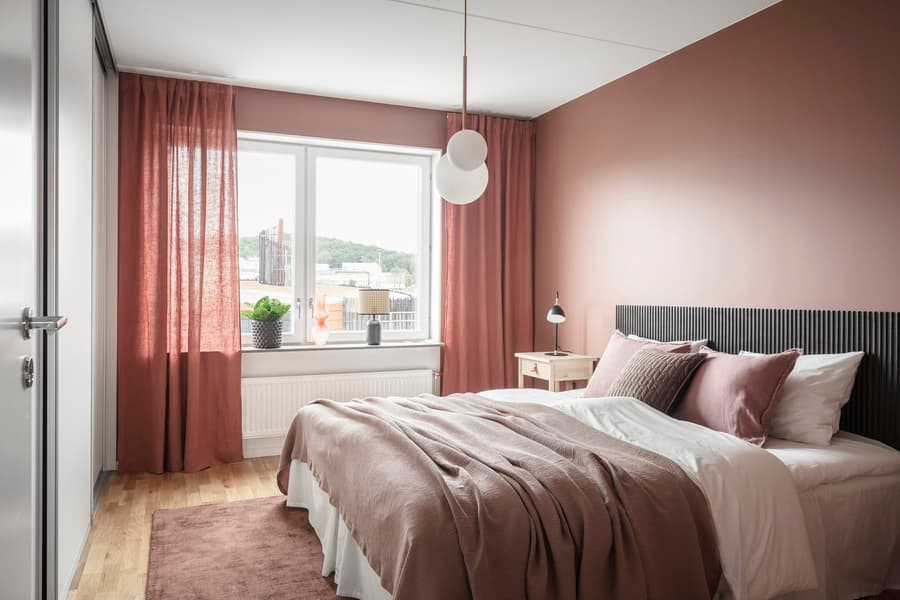 Sovrumsinredning. Väggar i korall och inredningsdetaljer i brunt och röda nyanser.