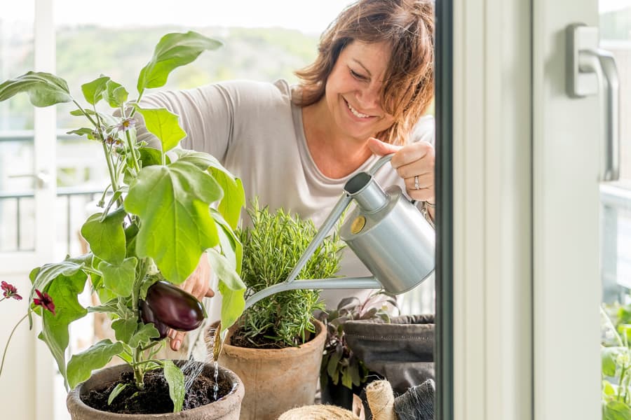 Kvinna på en JM balkong som tar hand om växter.