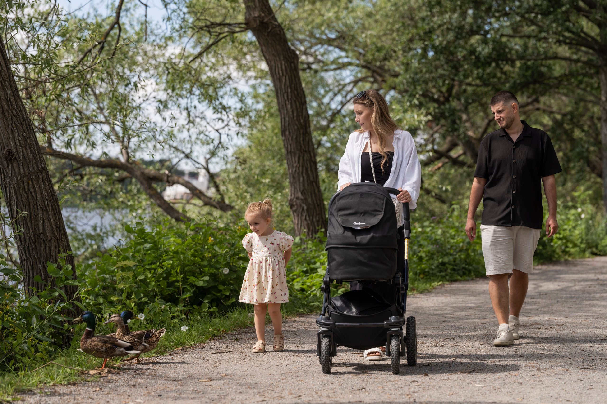 Mamma, pappa och dotter promenerar på en väg vid vattnet.